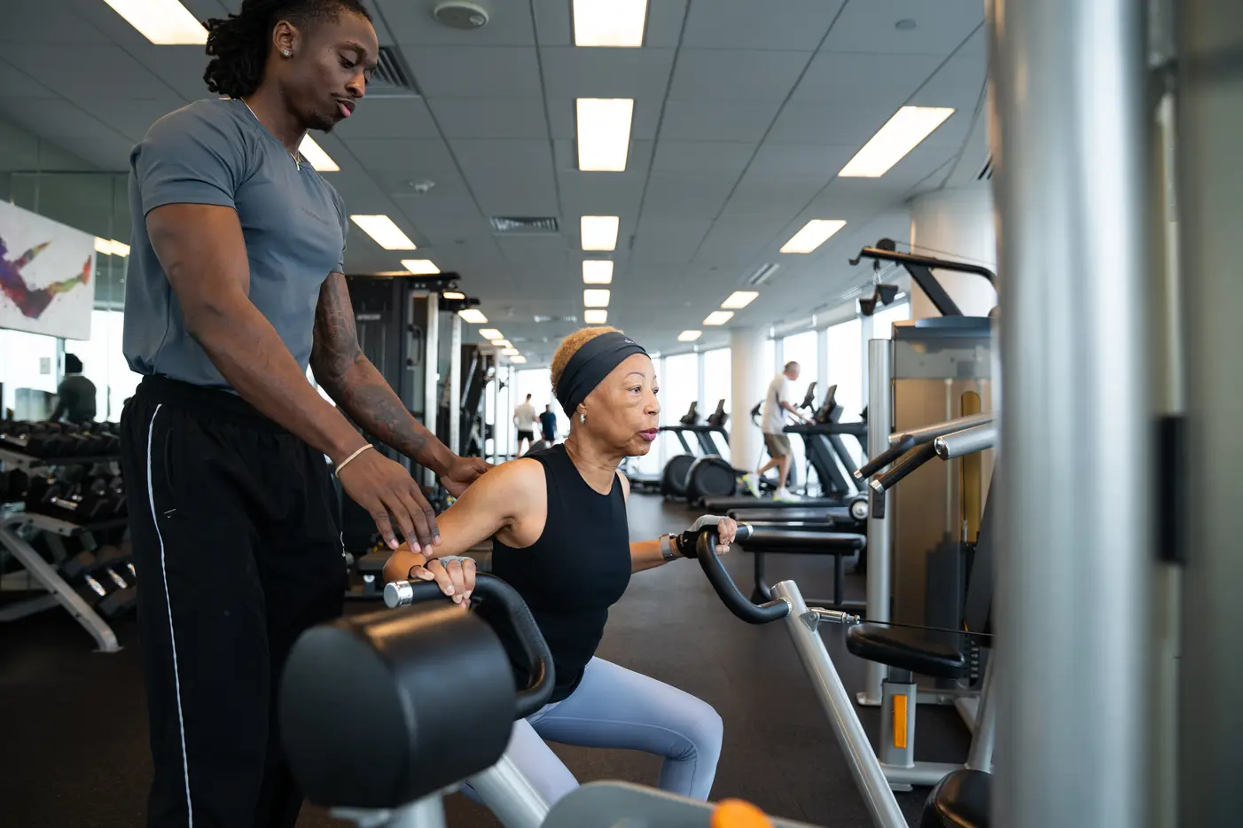 Chandler Thomas correcting a client's form on a seated row machine